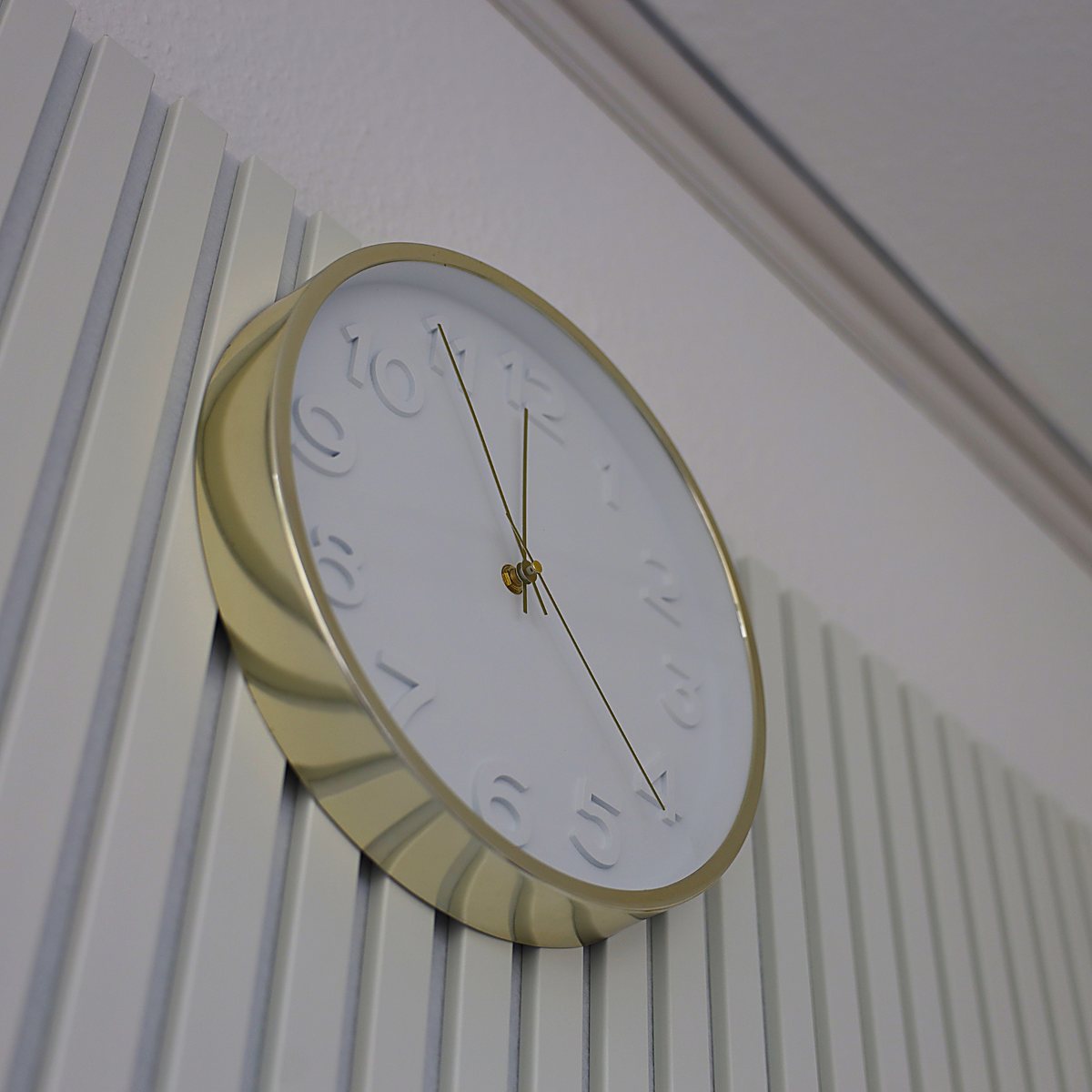 Elegantes Studio-Ambiente – goldene Wanduhr auf Lamellenwand